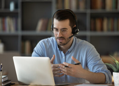 Confident man teacher wearing headset speaking, holding online lesson